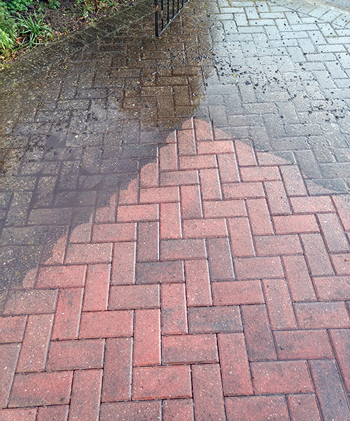Jet-washing a driveway showing the difference between dirty and clean